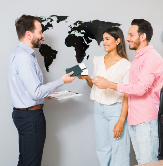 You are all set for your vacations. Sales representative giving passports and plane tickets to a young woman and man for their holiday trip at the travel agency